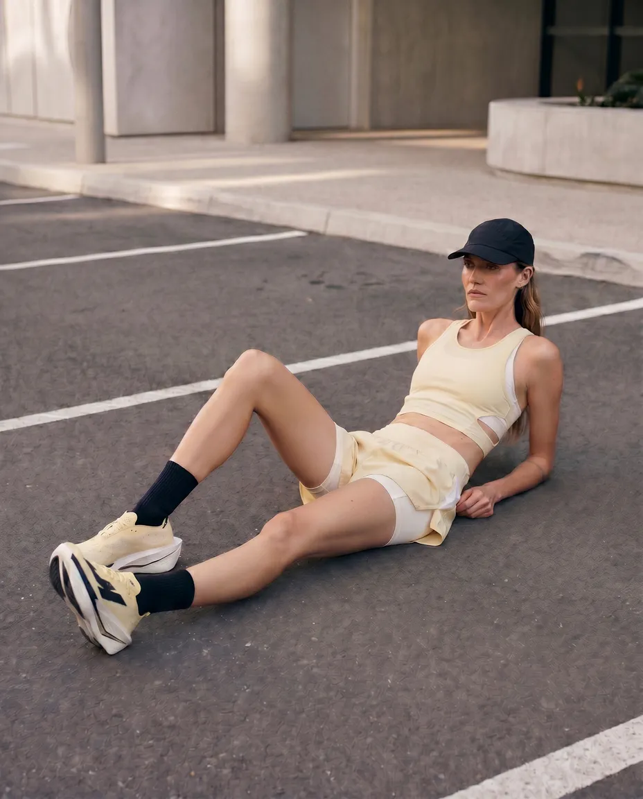 Runner in an "anti-performance" pose slouching against a raw brutalist concrete structure
